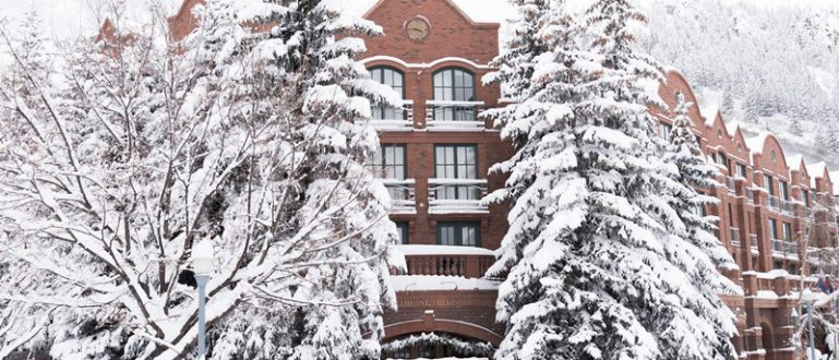 Hotel St. Regis Aspen cercado por árvores cobertas de neve.