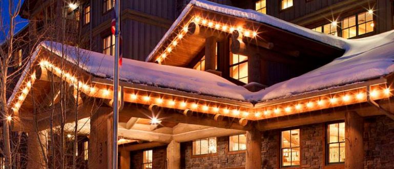 Entrada iluminada do Teton Mountain Lodge & Spa à noite, com neve ao redor.